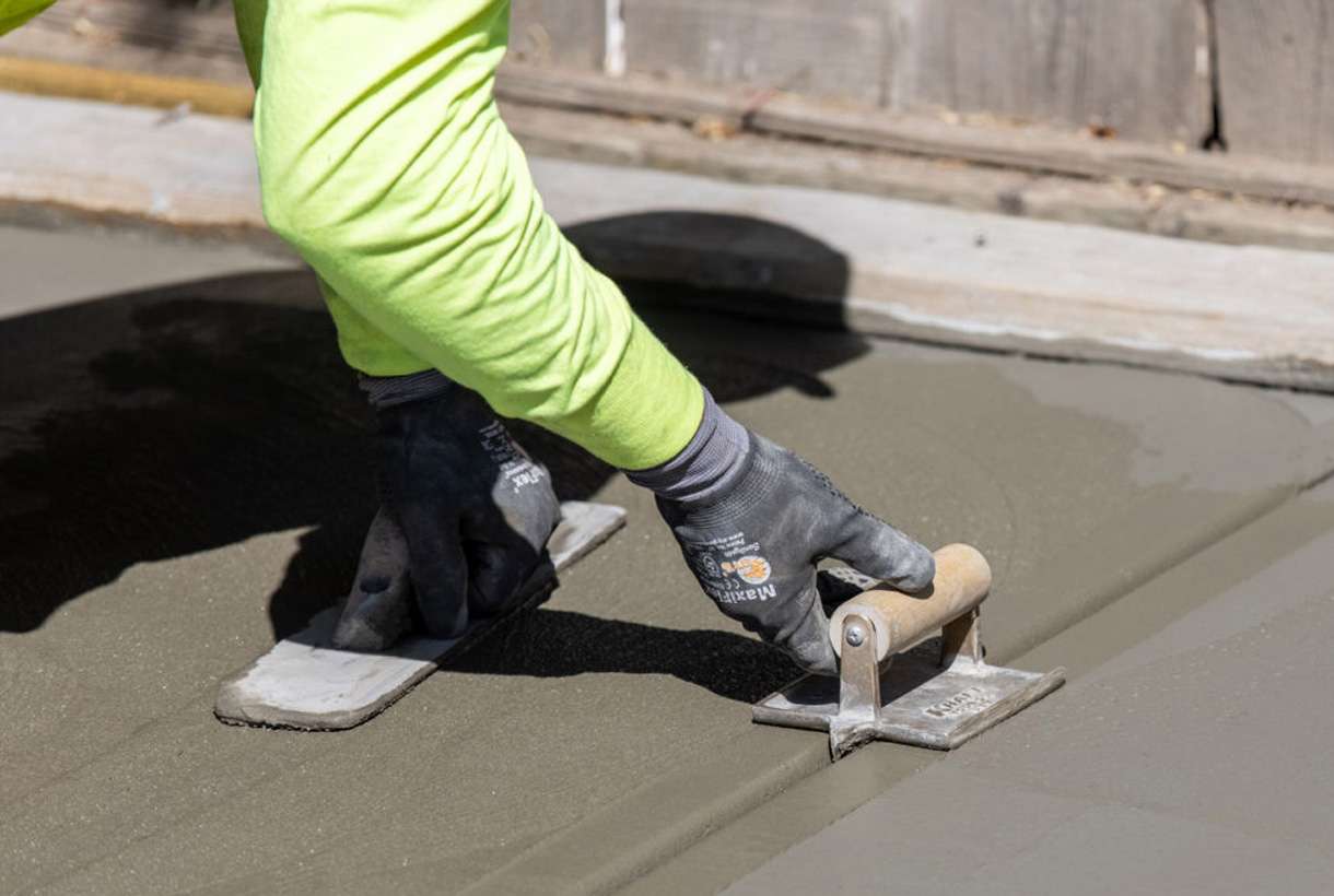 Construction worker troweling a groove in concrete