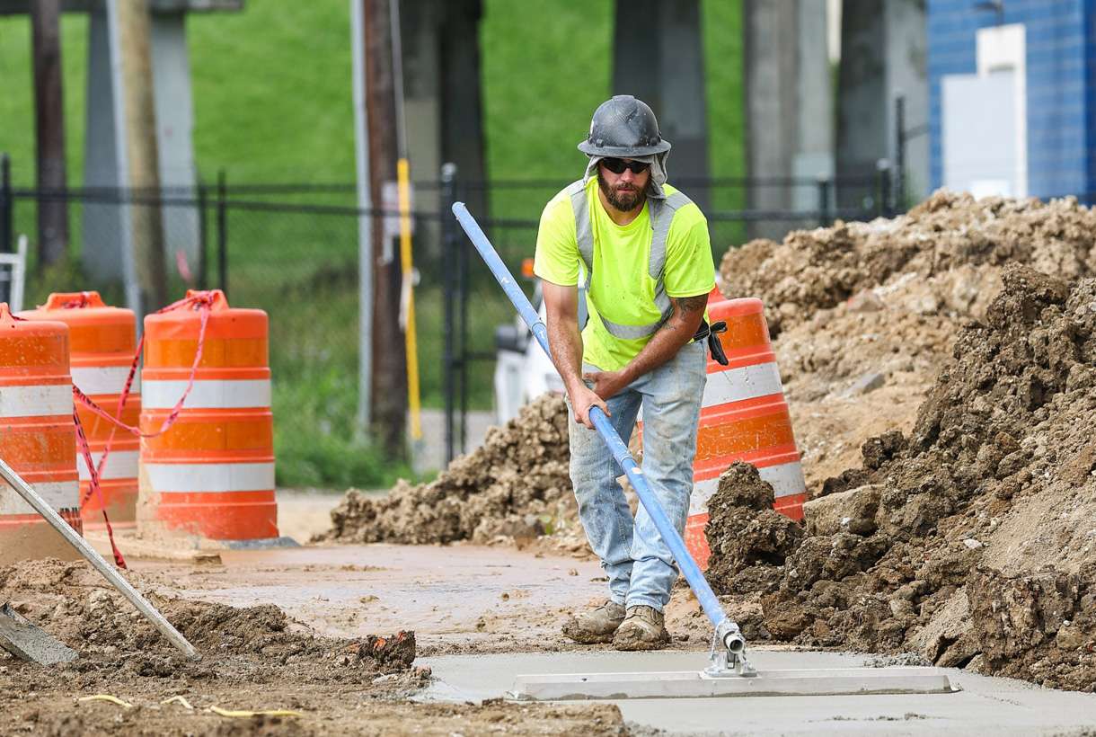 Construction worker bull floating a concrete footer