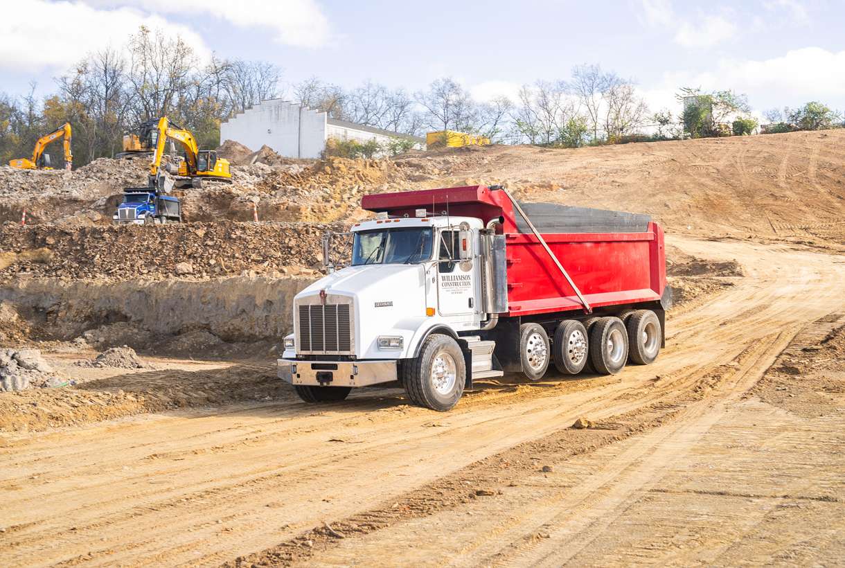 A red and white dump truck hauling out dirt on the construction jobsite